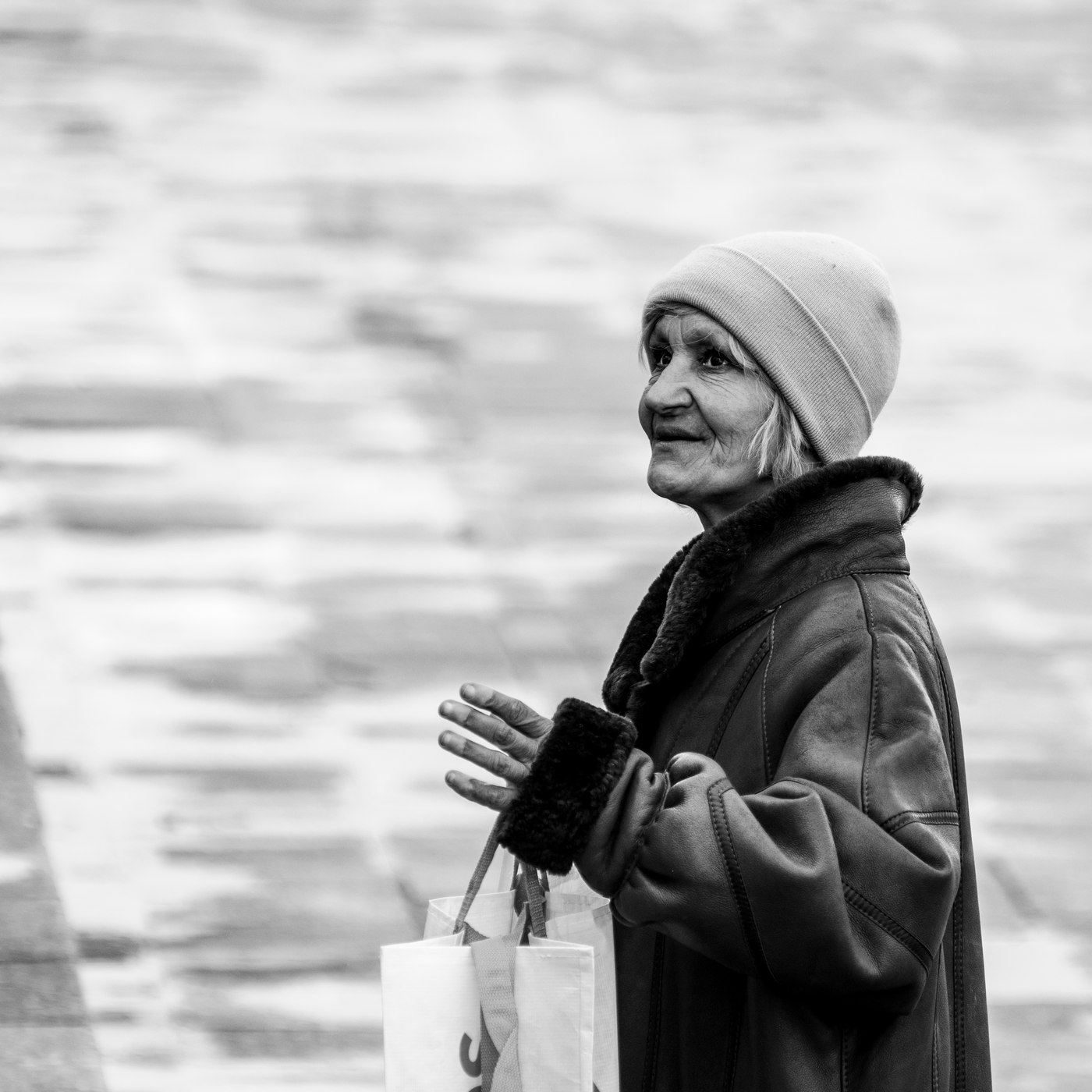 Portrait d'une femme dans la rue, bonnet et manteau, mains jointes